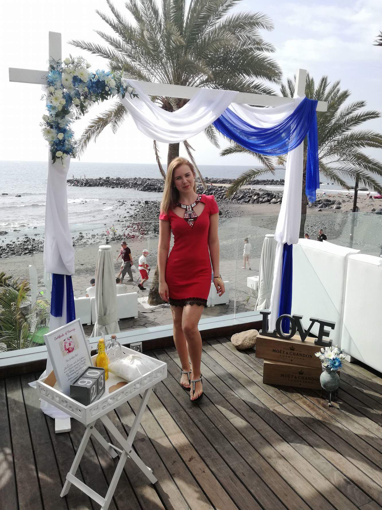 A girl with a red dress standing before the start of the wedding
